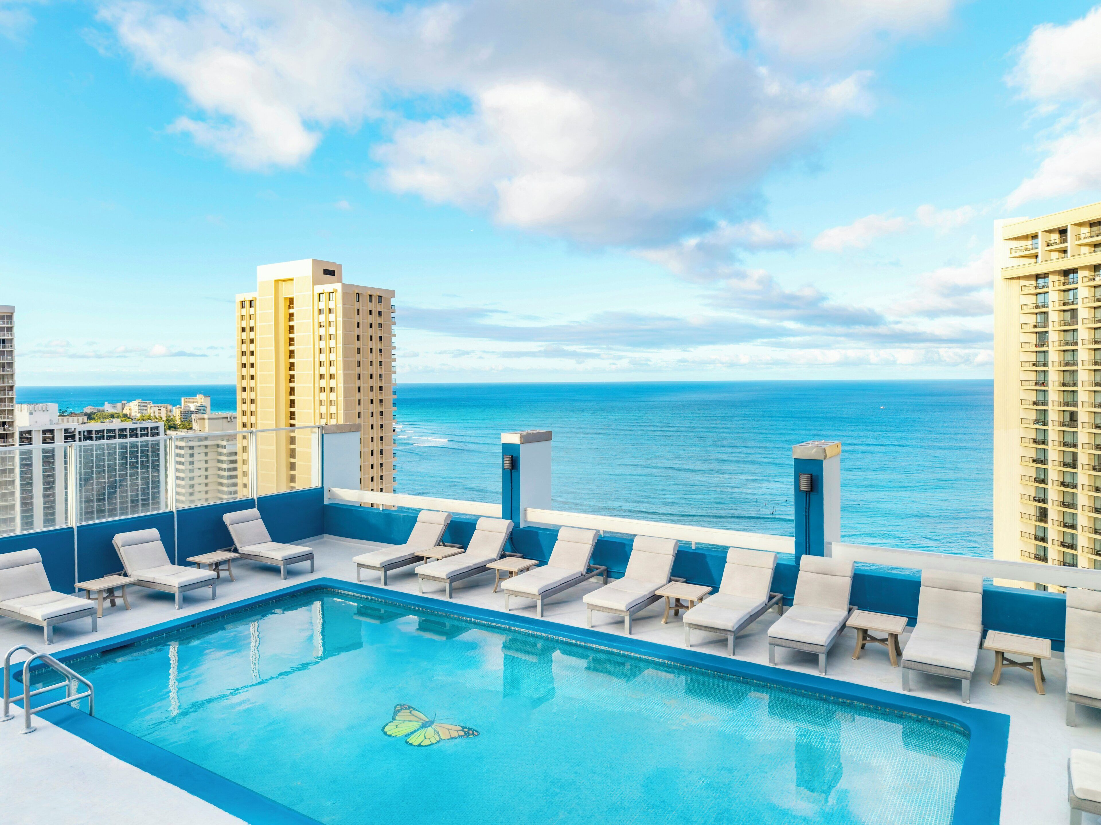 Piscina no terraço com espreguiçadeiras e vista para o mar.