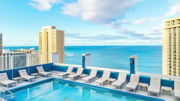 Piscina no terraço com espreguiçadeiras e vista para o mar.