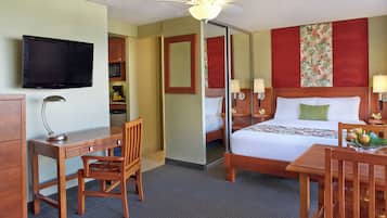 A hotel room with a bed, desk, chair, television, and a ceiling fan.