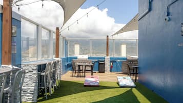 A rooftop patio with a grill, seating, and a view of the cityscape.