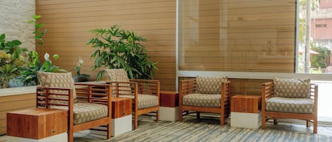 A room with a large window, wooden furniture, and potted plants.