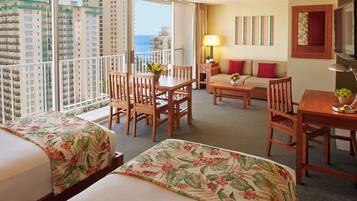 Quarto de hotel com duas camas, varanda, área de refeições e um sofá.
