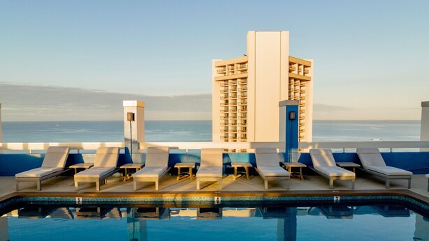 A poolside area with lounge chairs and a view of the ocean. - Pacific Monarch Hotel (Honolulu)