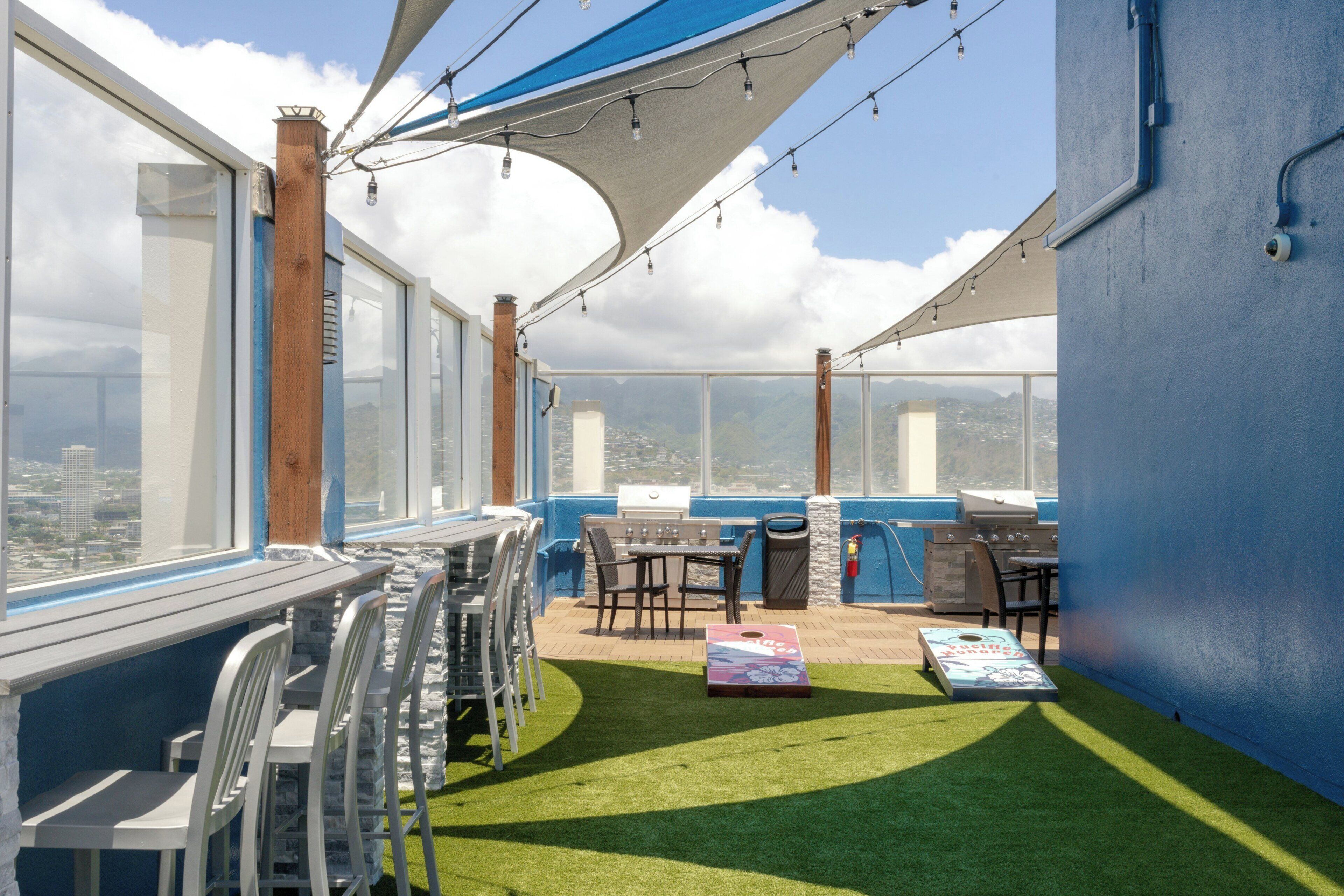 A rooftop terrace with a dining area, barbecue grill, and a view of the cityscape.