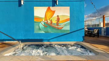 A hot tub with a mural of a sailboat on a blue wall.