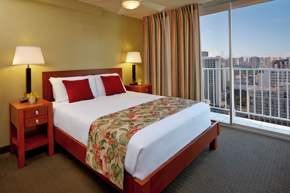 A hotel room with a large bed, two bedside tables, a nightstand, a window with curtains, and a city view.