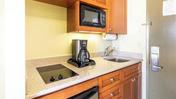 Una cocina compacta equipada con microondas, cafetera, lavabo y lavavajillas.
