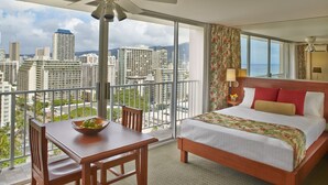 A hotel room with a balcony, a bed, a dining table, and chairs. - Pacific Monarch Hotel (Honolulu)