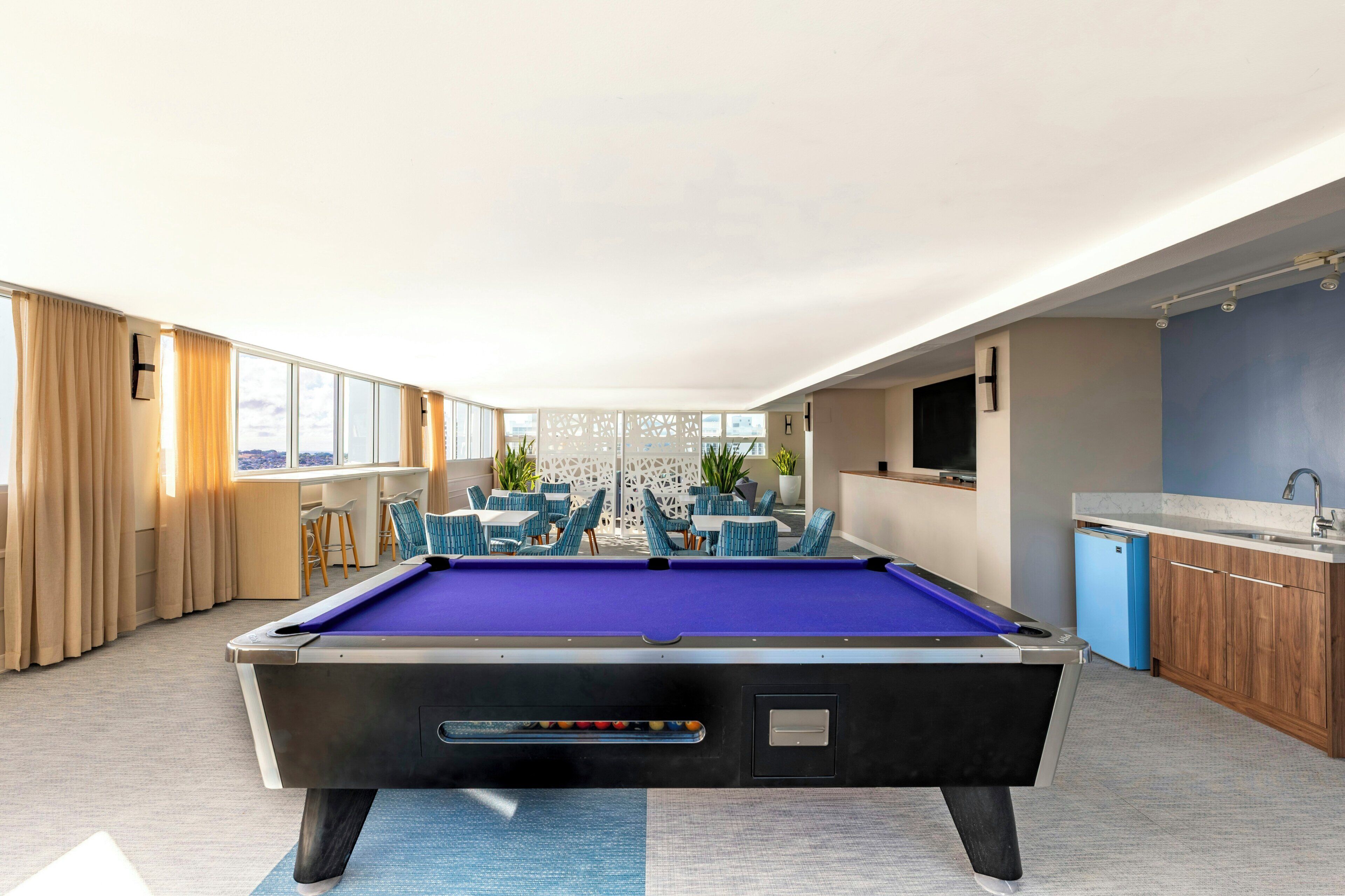 Mesa de bilhar em ambiente com vista, bar e área de estar.