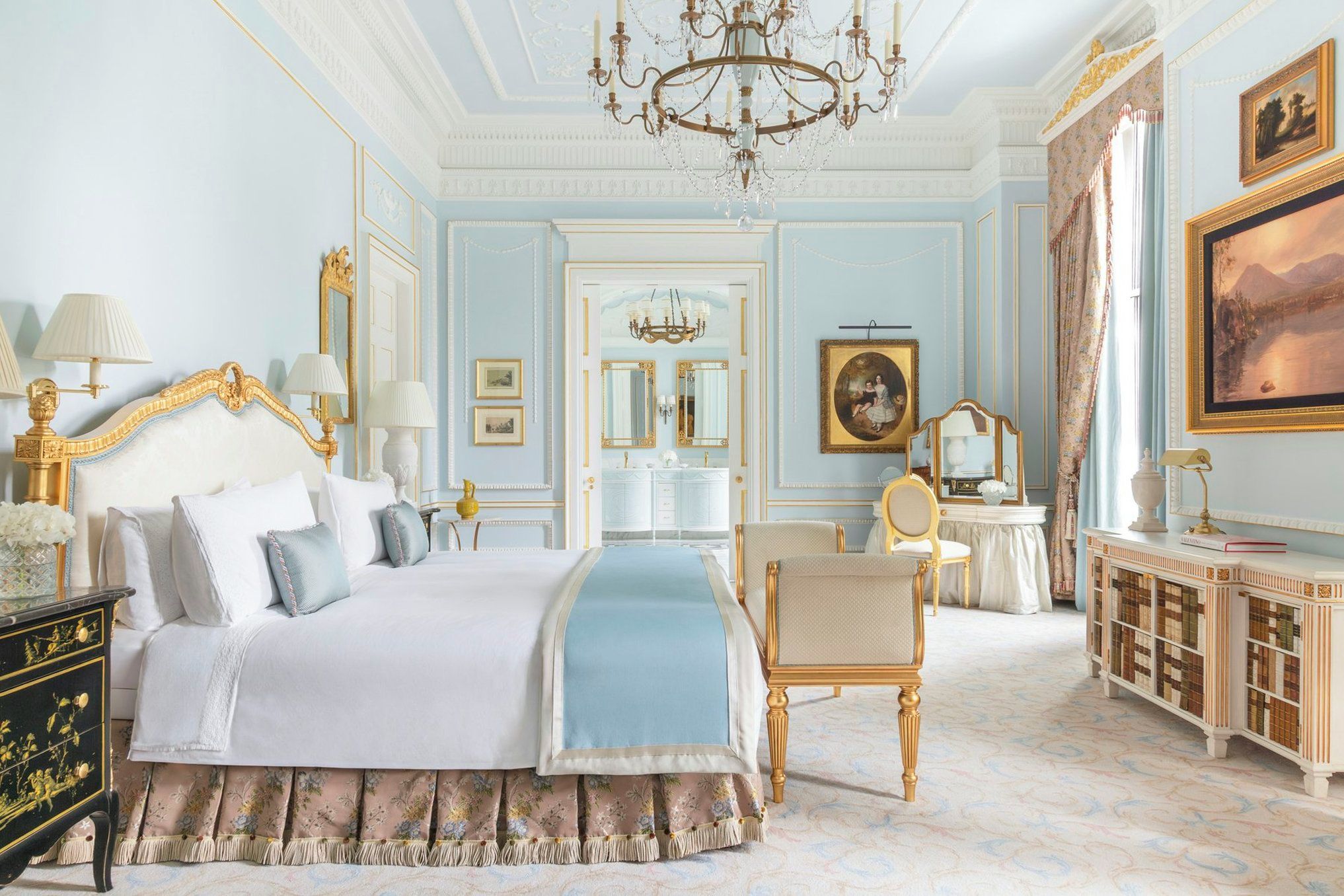 A spacious bedroom with a large bed, a sitting area, and a vanity with a mirror.