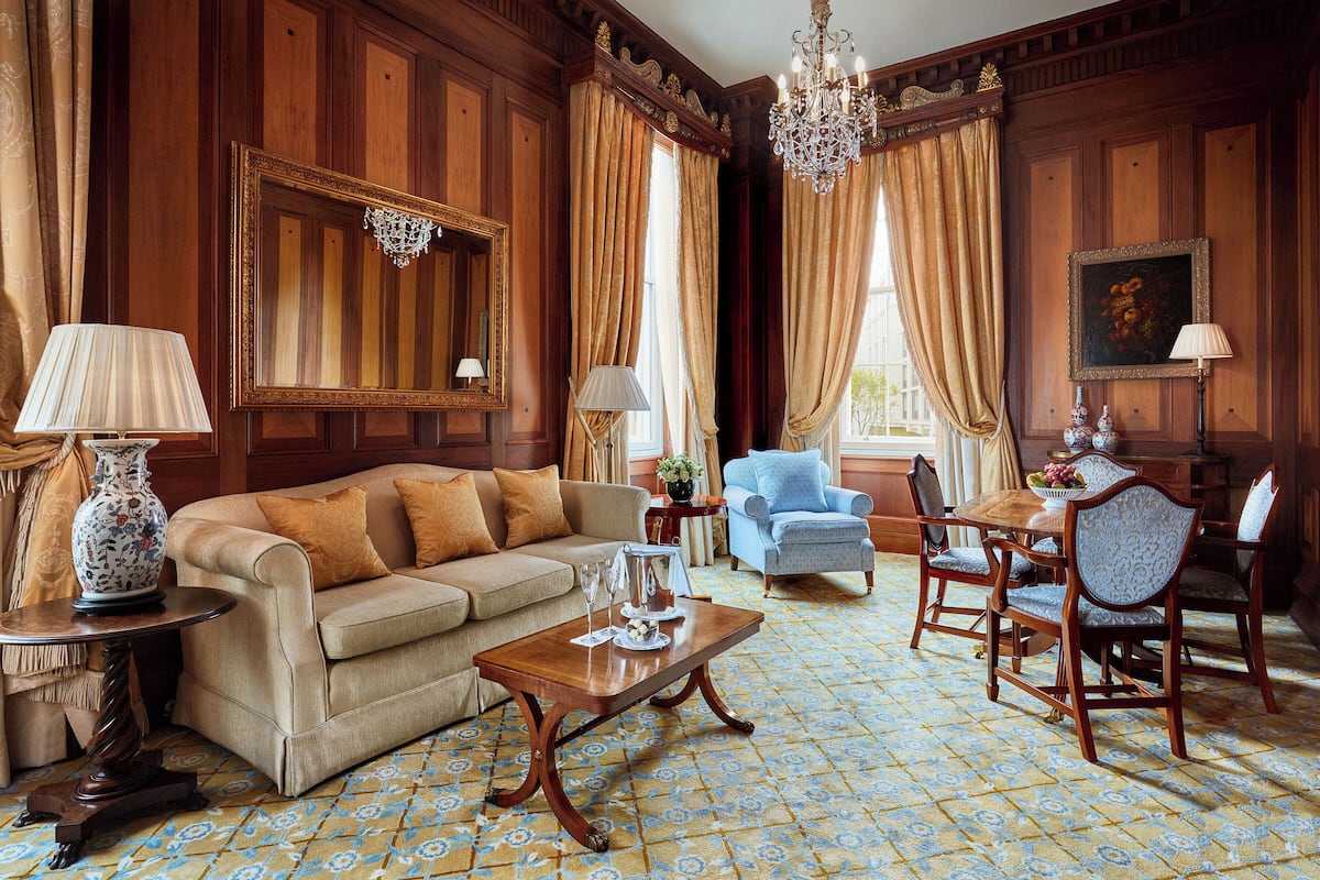 Una habitación con pared de paneles de madera, un sofá, una mesa de centro, un sillón azul y una mesa de comedor con sillas.