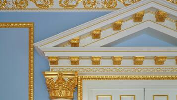A room with a white door, gold decorative moldings, and a blue wall.