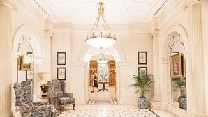 A grand lobby with ornate chandeliers, classical columns, and a patterned floor. - The Lanesborough, Oetker Hotels (London)