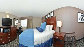 Una habitación de hotel con cama, escritorio, televisión y silla.