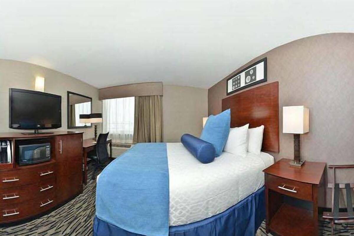 Una habitación de hotel con cama, escritorio, televisión y silla.