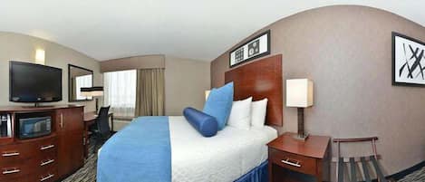 A hotel room with a bed, a desk, a television, and a chair.