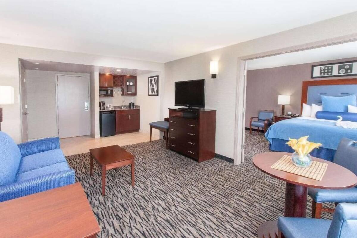 Habitación de hotel con cama, televisión, escritorio, silla, sofá y kitchenette.