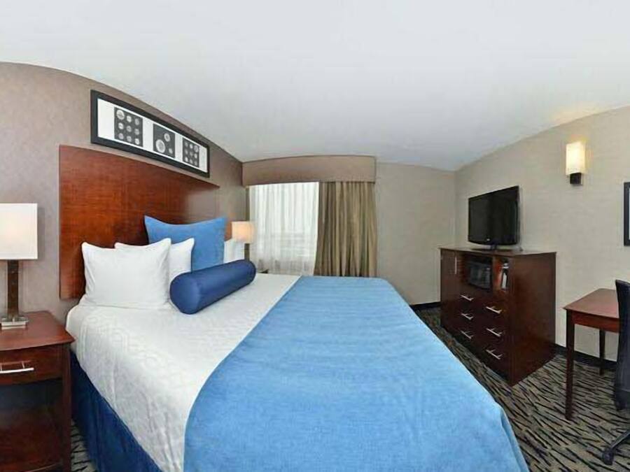 A hotel room with a large bed, a desk, a chair, a television, and a framed picture on the wall.