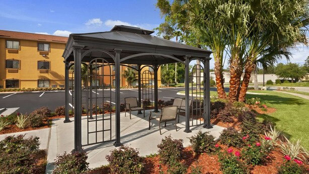 A covered outdoor seating area with chairs and a palm tree. - Days Inn by Wyndham Orange Park/Jacksonville (Orange Park)