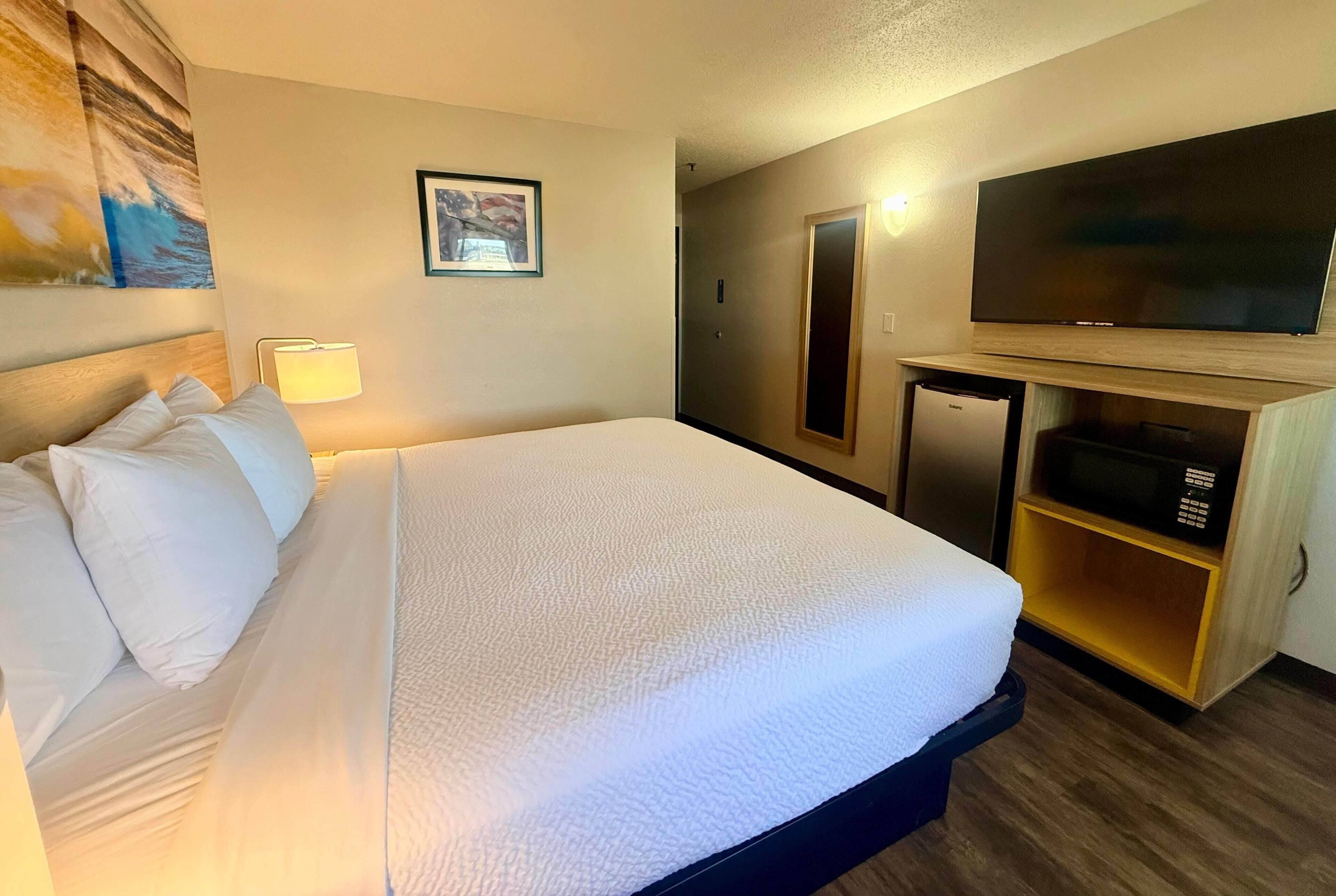 Habitación de hotel con cama, televisión, microondas y un mueble pequeño.