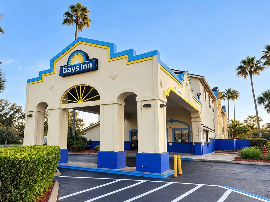 A Days Inn with a distinctive blue and yellow facade, a parking lot, and palm trees in the background.