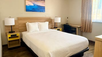 Una camera d'albergo con un letto grande, due comodini con lampade, un quadro raffigurante un tramonto e una finestra con tende.