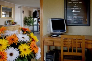 A hotel room with a desk, a computer monitor, a chair, a desk lamp, a flower arrangement, and a wall-mounted menu board. - Americas Best Value Inn & Suites Murfreesboro (Murfreesboro)