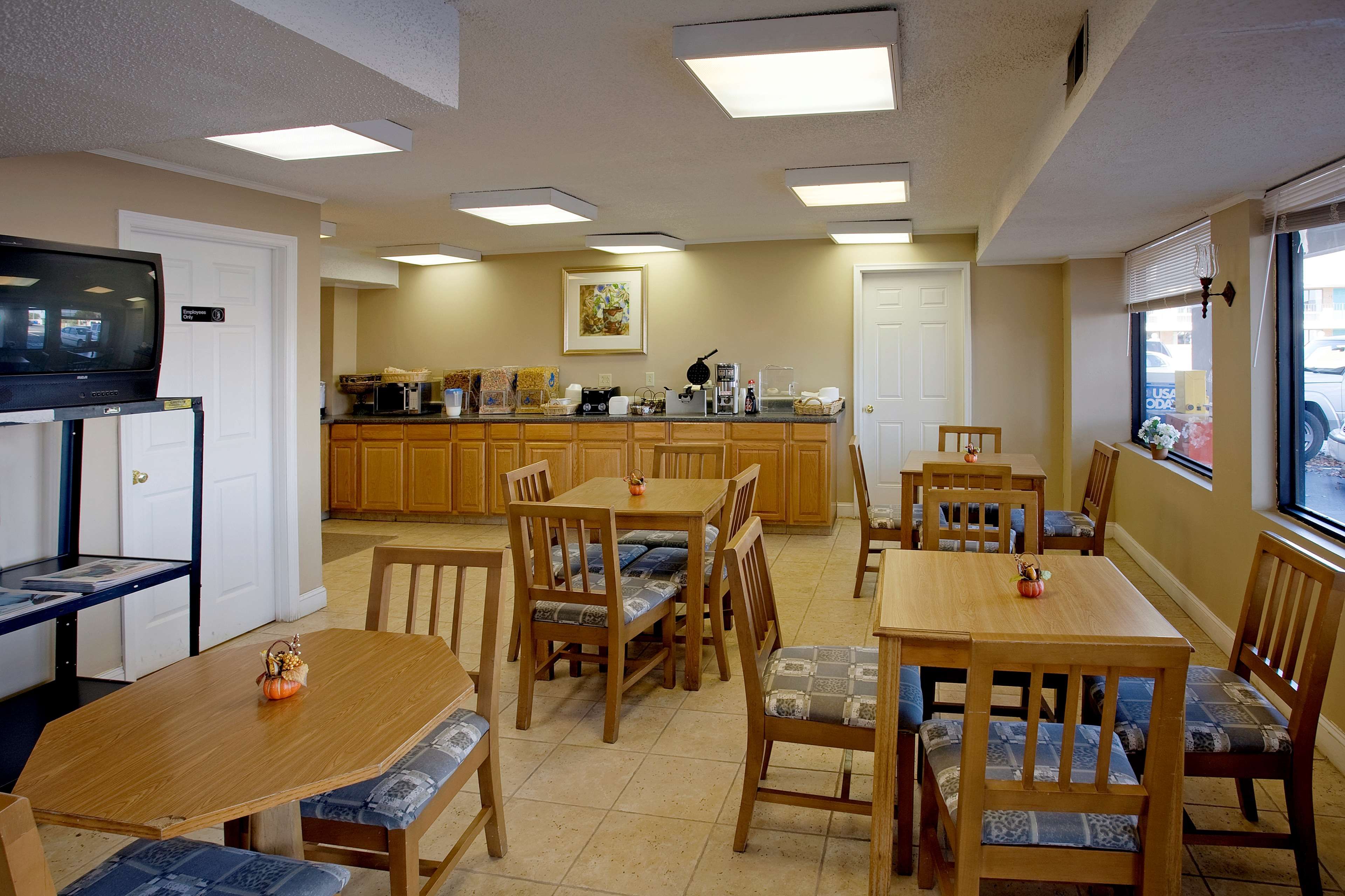 A hotel room with a dining area, kitchen, and a television.