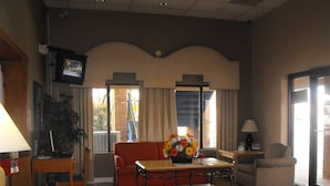 A hotel room with a sofa, a coffee table, a TV, and a window with curtains. - Americas Best Value Inn & Suites Murfreesboro (Murfreesboro)