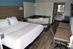 A hotel room with a bed, a desk, a chair, a small kitchenette, and a bathroom with a bathtub. - Americas Best Value Inn & Suites Murfreesboro (Murfreesboro)