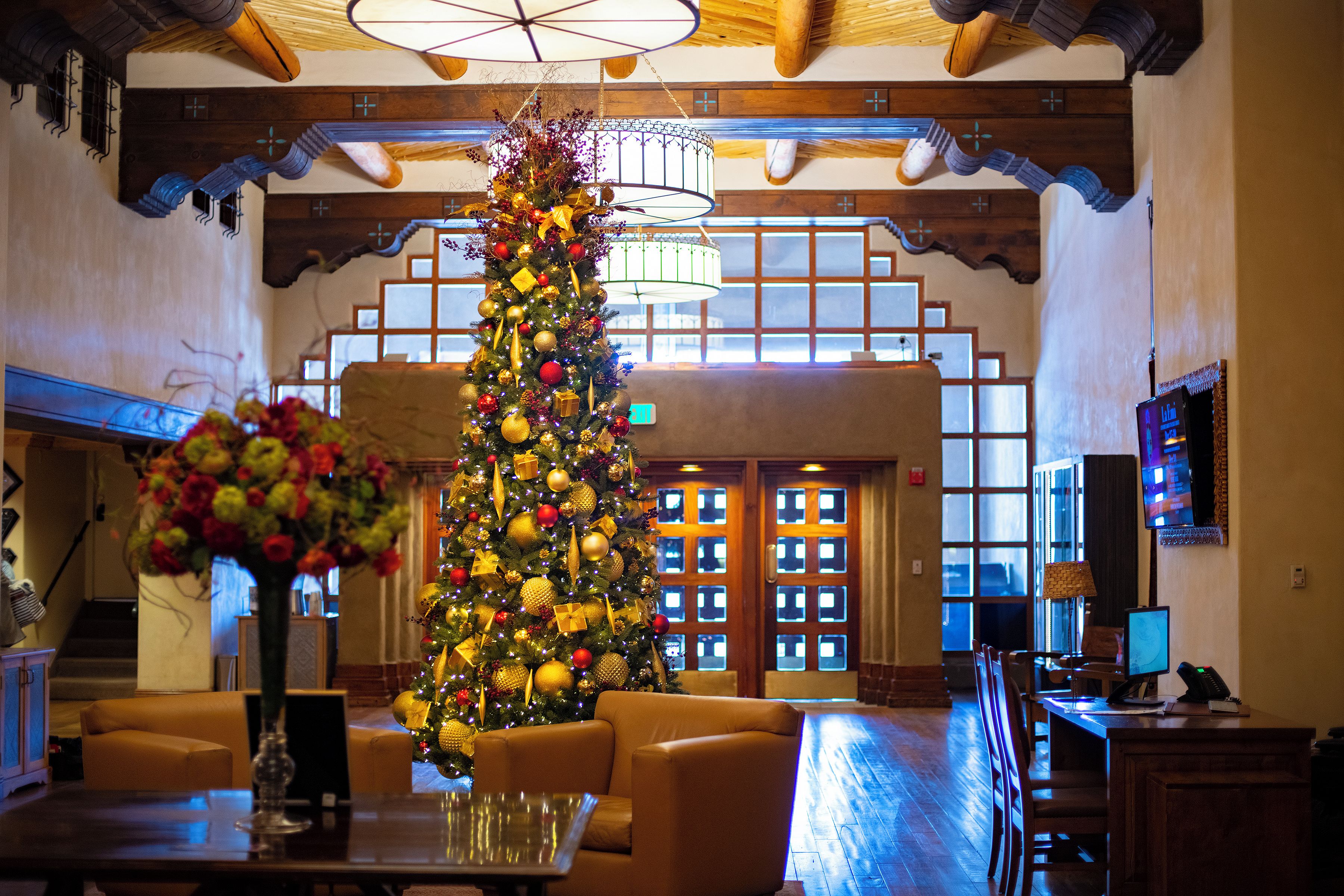 A lobby with a large Christmas tree, leather seating, a reception desk, and a television.