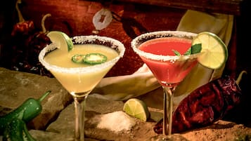 Two cocktails with lime slices and a salt rim, surrounded by green chili peppers and a rustic wooden background.