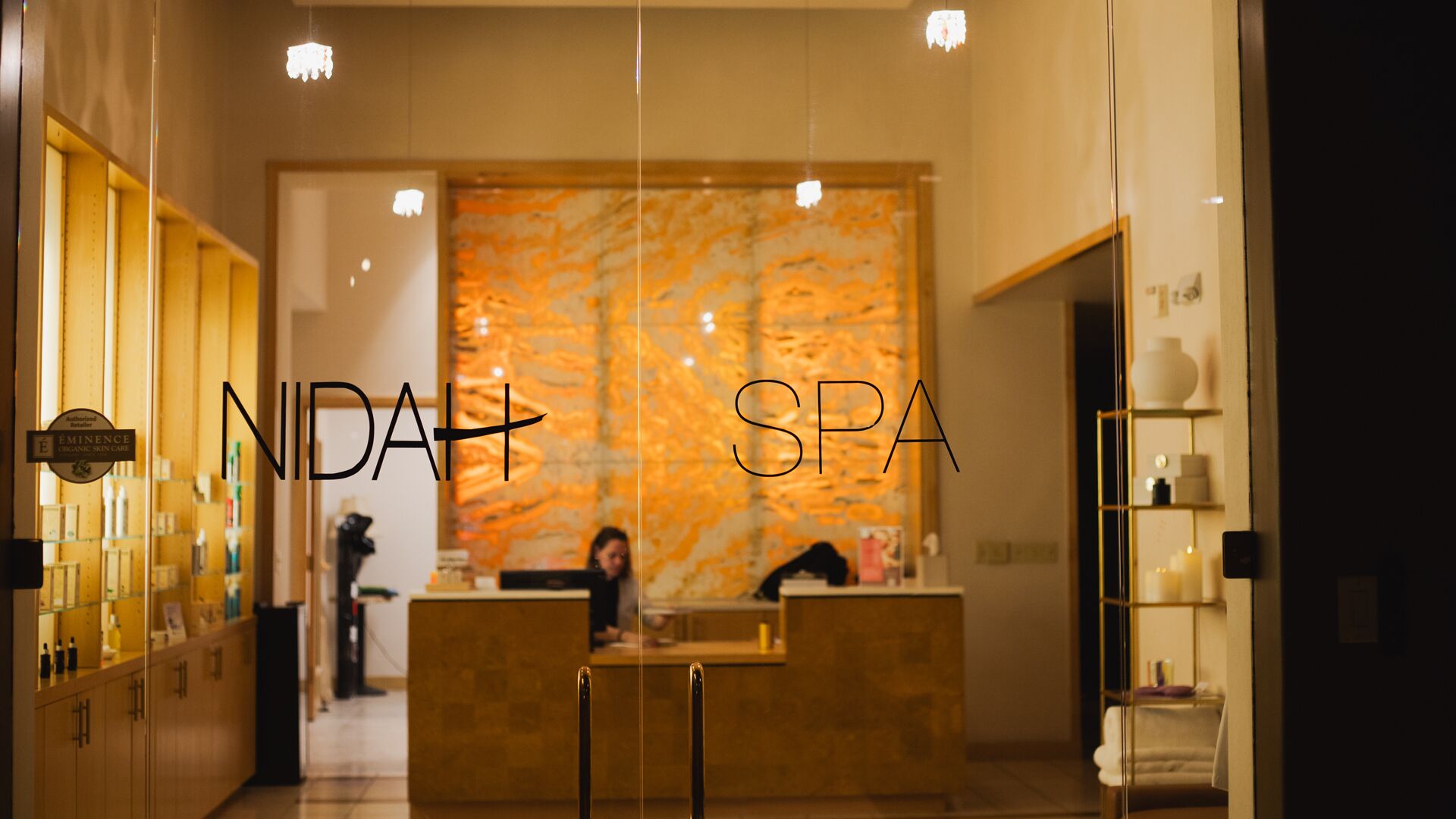 A reception area with a reception desk, a wall with a textured pattern, and a sign indicating the spa name.