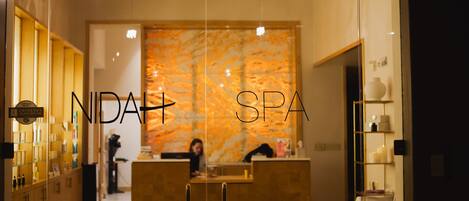 A reception area with a reception desk, a wall with a textured pattern, and a sign indicating the spa name.