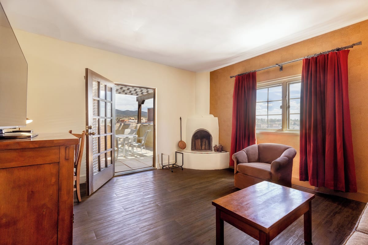 Una sala de estar con chimenea, una mesa de madera, un sofá y vistas a través de un ventanal.