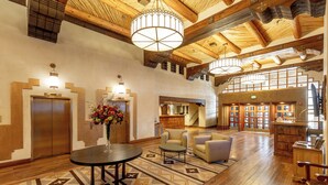 A spacious lobby with wooden floors, a round table with a vase of flowers, and a staircase leading to upper levels. - Eldorado Hotel & Spa (Santa Fe)