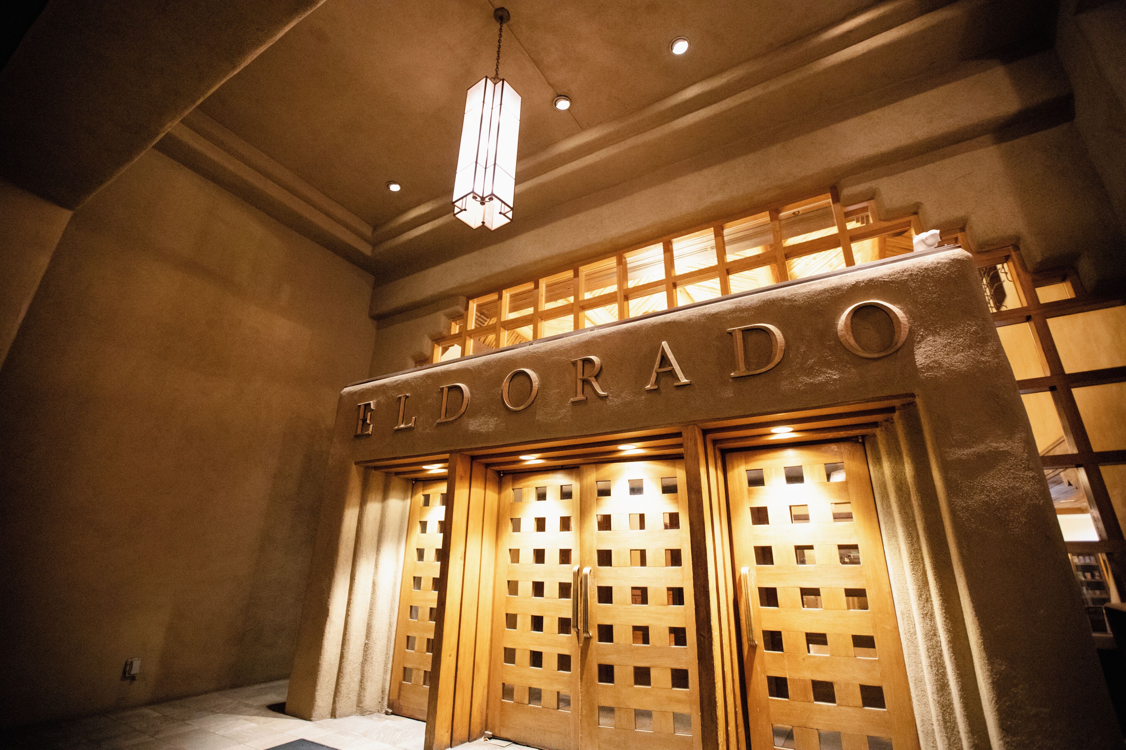 A hotel entrance with a sign reading 'EL DORADO' and a modern design with wooden panels and a hanging light fixture.