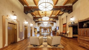 A spacious hotel lobby with wooden floors, a central seating area, and a high ceiling with exposed beams. - Eldorado Hotel & Spa (Santa Fe)