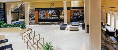 Un hall d’entrée spacieux avec un escalier central, des coins salon et un bar.