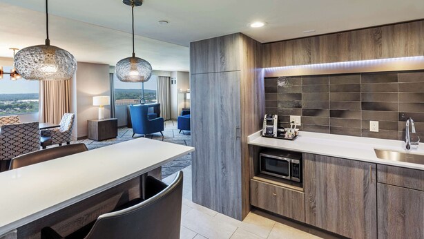 Una cocina moderna con horno empotrado, un lavamanos y una zona de comedor con mesa y sillas.