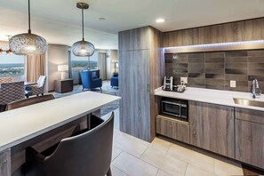A modern kitchen with a built-in oven, a sink, and a dining area with a table and chairs. - DoubleTree by Hilton Tulsa Downtown (Tulsa)
