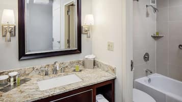 A bathroom with a marble sink, a large mirror, a shower, and a toilet.