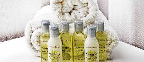 A set of five bottles of Verbena and Lavender body wash and conditioner, each labeled with 24ml/8.8fl oz, placed in front of a white towel.
