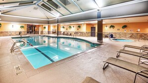 Una amplia piscina interior con varias pistas, sillas de descanso y una zona de piscina más pequeña separada.