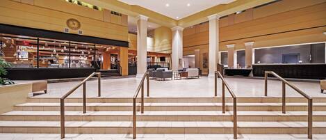 Eine geräumige Lobby mit einer zentralen Treppe, einer Sitzecke und einer Rezeption.