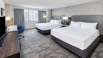 A hotel room with two beds, a desk, and a chair.