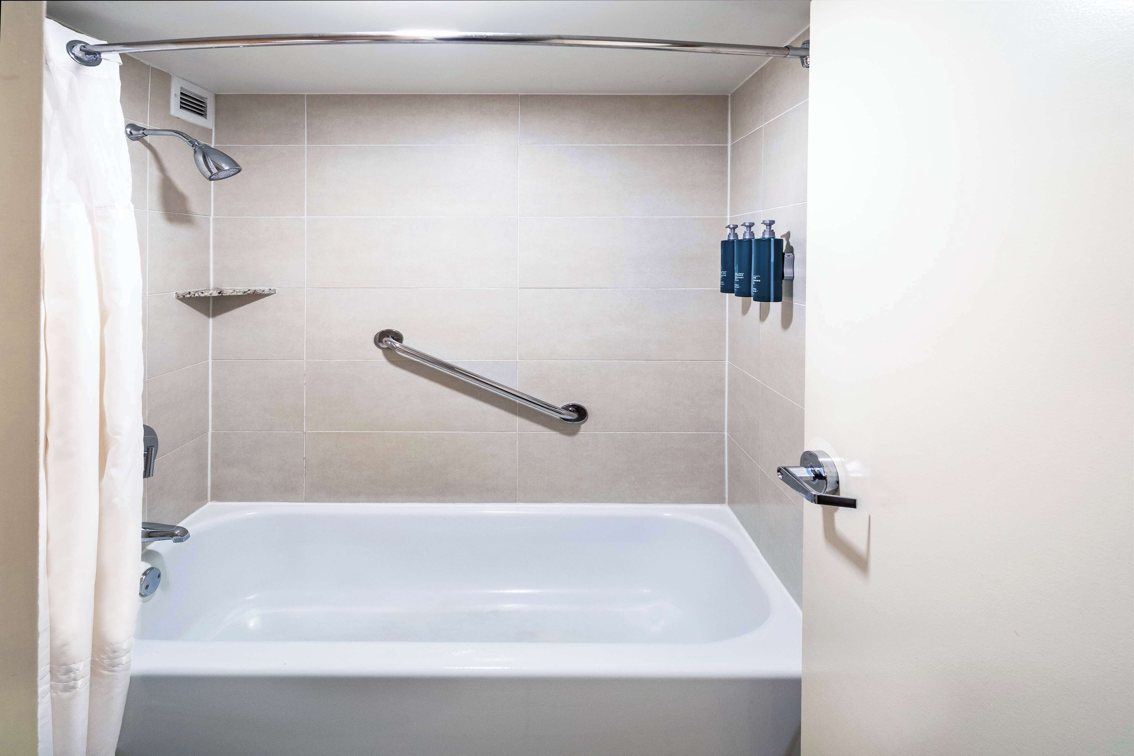 Une salle de bain équipée d’une baignoire, d’une douche et d’une barre d’appui.