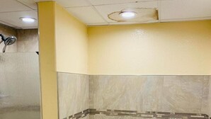 A bathroom with a large bathtub, a glass shower enclosure, and beige tiled walls. - Coachman's Inn (Magnolia)