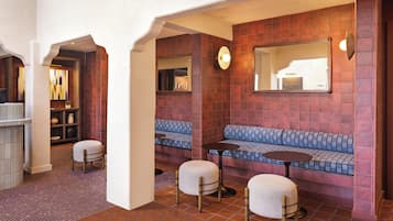 A seating area with a bench, two round tables, and a chair.