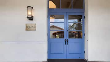 A blue door with a 'FOUND' sign above it, a wall-mounted light, and a view of a building through the door's glass panels.